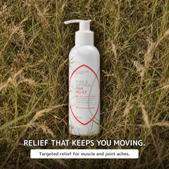 A white pump bottle labeled 'Pure & Natural Pain Relief Cream' stands upright in tall dry grass outdoors. Text below reads 'RELIEF THAT KEEPS YOU MOVING.