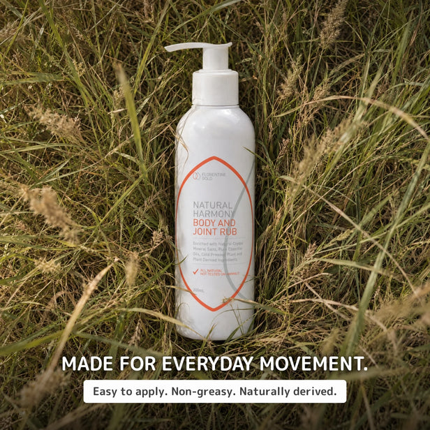 A white pump bottle of Natural Harmony Body and Joint R&B supplement placed upright in tall dry grass. The label features orange and gray text, and the image includes the text 'MADE FOR EVERYDAY MOVEMENT.